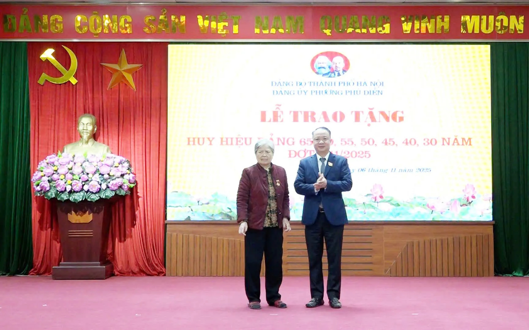 นายเหงียน เล ฮวง เลขาธิการพรรค ประธานสภาประชาชนแขวงฟู่เดียน มอบป้ายสมาชิกพรรคครบรอบ 65 ปี ให้กับสมาชิกพรรค Bí thư Đảng ủy, Chủ tịch HĐND phường Phú Diễn Nguyễn Lê Hoàng trao Huy hiệu 65 năm tuổi Đảng tặng đảng viên