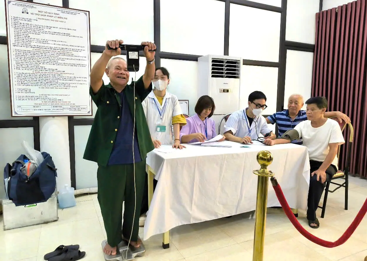 A person standing on a scale with a group of people in the background  Description automatically generated