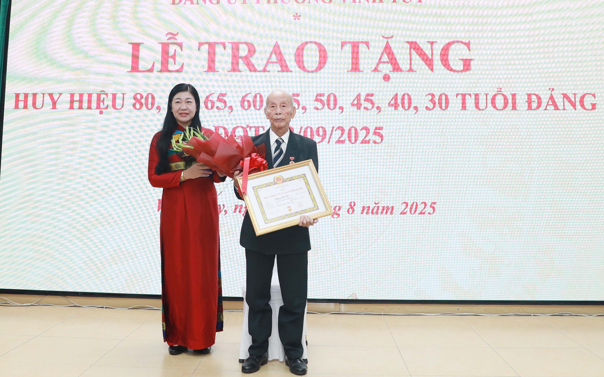 Chủ tịch Ủy ban MTTQ Việt Nam Thành phố Nguyễn Lan Hương trao Huy hiệu 70 năm tuổi Đảng, tặng hoa chúc mừng đảng viên Hoàng Văn Việt