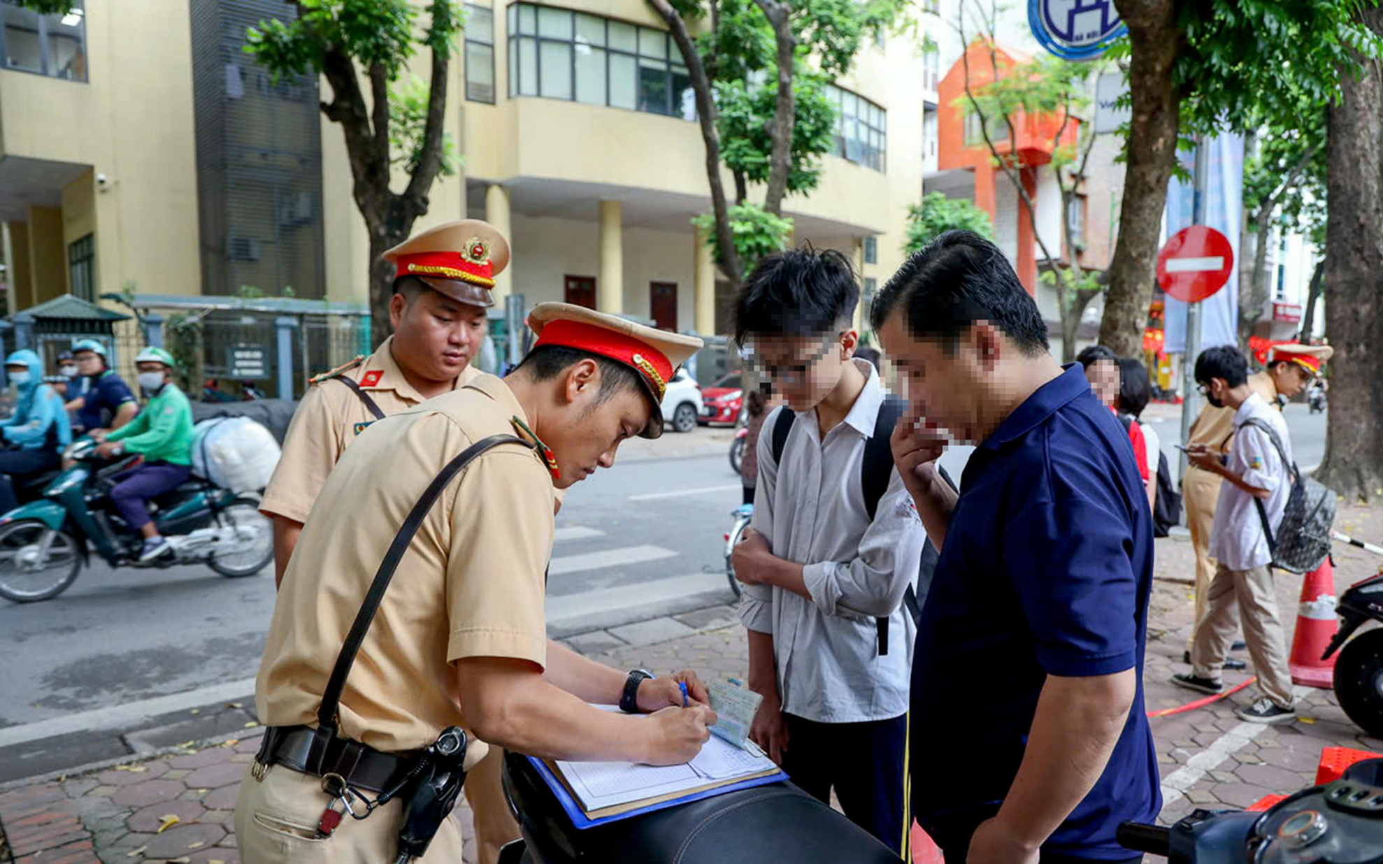 Trong ảnh, phụ huynh điều khiển xe máy chở con đi học nhưng nam sinh ngồi sau không đội mũ bảo hiểm.