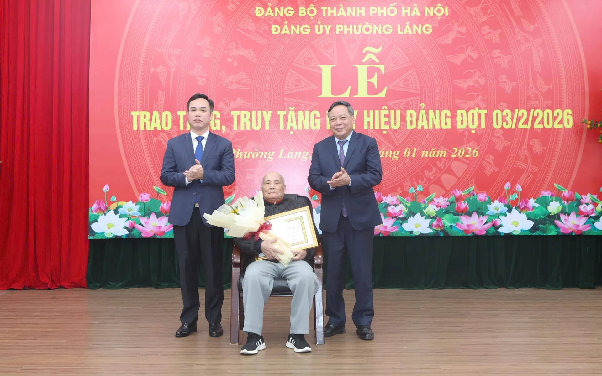 Phó Bí thư Thường trực Thành ủy Hà Nội Nguyễn Văn Phong và lãnh đạo phường Láng trao Huy hiệu 80 năm tuổi đảng và tặng hoa chúc mừng đảng viên lão thành.