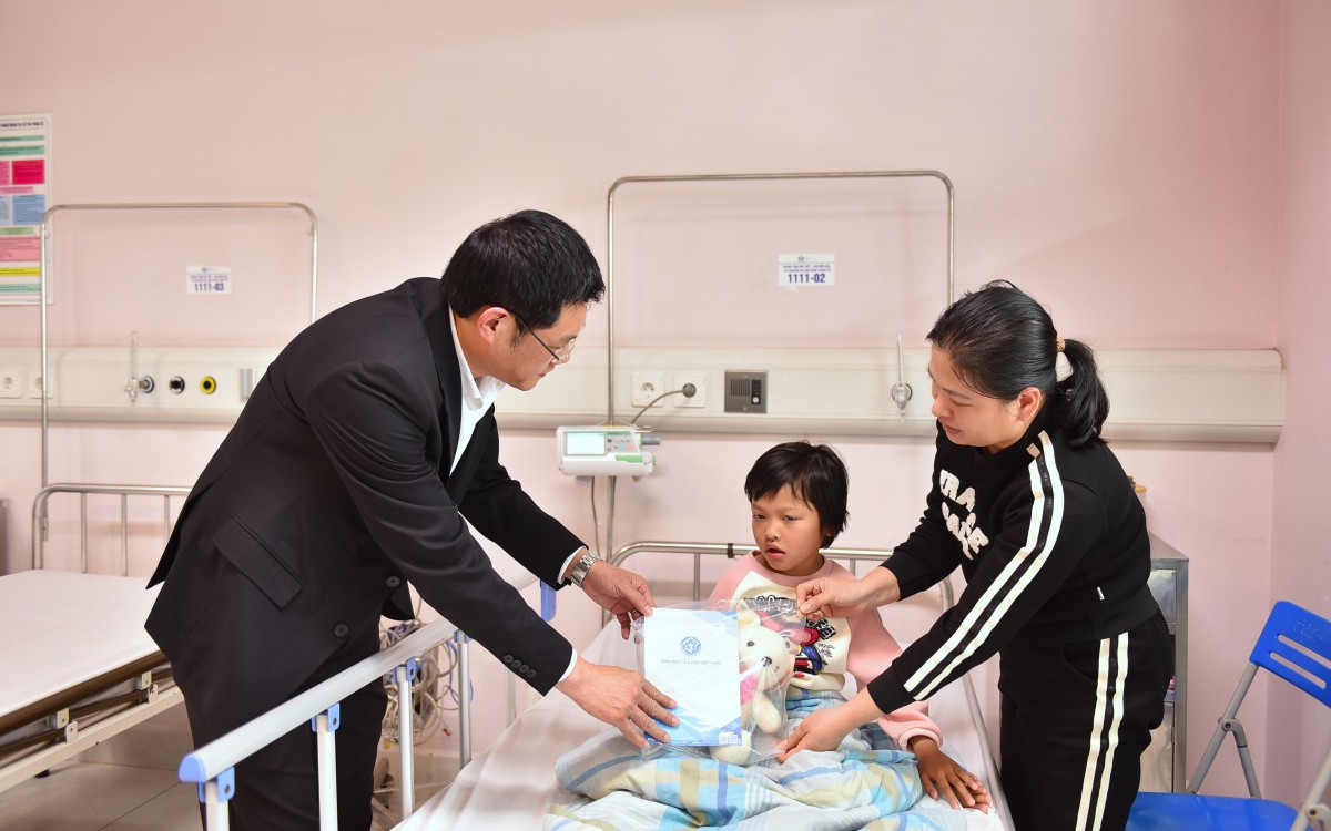 Giám đốc BHXH thành phố Hà Nội Nguyễn Ngọc Huyến tặng quà cho bệnh nhi có hoàn cảnh khó khăn.