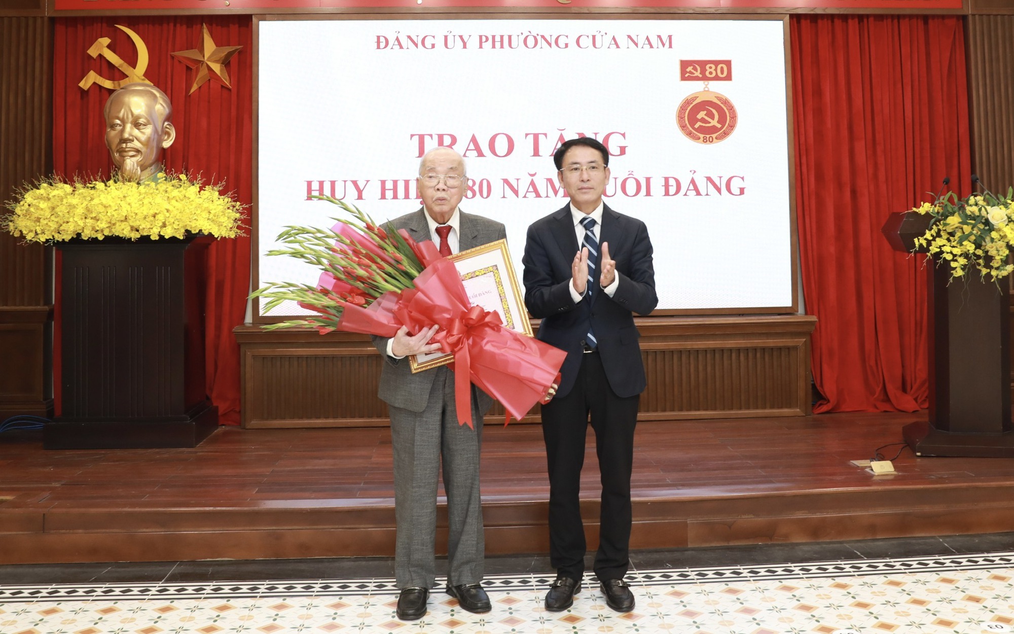 Phó Bí thư Thành ủy Nguyễn Trọng Đông trao Huy hiệu và tặng hoa chúc mừng đảng viên Nguyễn Tiến Hà